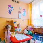 Trójka dzieci stoi przy czerwonym stole