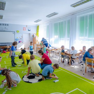 Dzieci bawią się na podłodze i rysuja przy stolikach