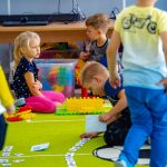 Dzieci bawią się zabawkami na zielonej podłodze