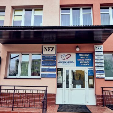 Wejście do przychodni lekarskich. Nad białymi drzwiami, a także po obu bokach szyldy