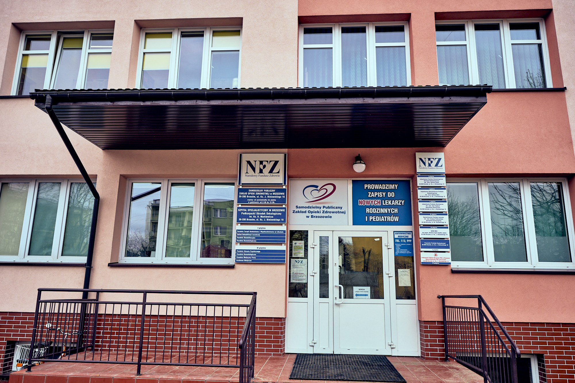 Wejście do przychodni lekarskich. Nad białymi drzwiami, a także po obu bokach szyldy