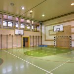 Sala sportowa z boiskiem do piłki ręcznaj. Na ścianach wiszą kosze do koszykówki