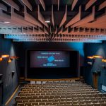 Kolorowo iluminowana sala kinowa z rzędami jasnych krzeseł