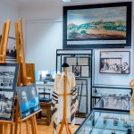 Eksponaty muzealne w gablotach oraz stare zdjęcia ustawione na sztalugach