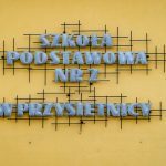 Napis z metalowych liter umieszczony na żótej elewacji budynku