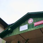 Daszek nad wejściem z dwoma szyldami i godłem Polski po środku