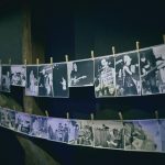 Dwa rzędy czarno-białych fotografii przymocowanych klamerkami na sznurkach