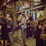 Tłum ludzi w w pomieszczeniu na poddaszu z drewnianymi filarami