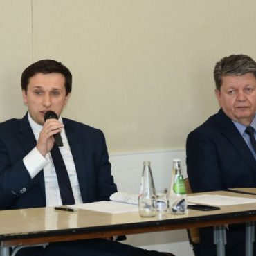 Młody mężczyzna w garniturze odpowiadania na zadane pytanie do mikrofonu.