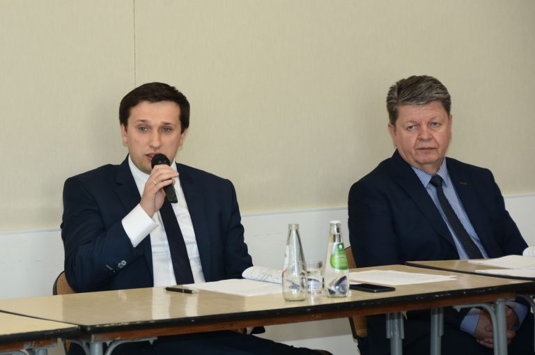 Młody mężczyzna w garniturze odpowiadania na zadane pytanie do mikrofonu.