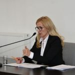 Kobieta o blond włosach przemawia do mikrofonu.