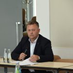 Mężczyzna w średnim wieku słucha wypowiedzi innych osób.