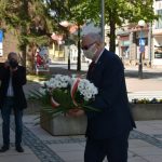 Starszy mężczyzna składa kwiaty pod pomnikiem