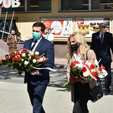 Młody mężczyzna i kobieta składają kwiaty pod pomnikiem