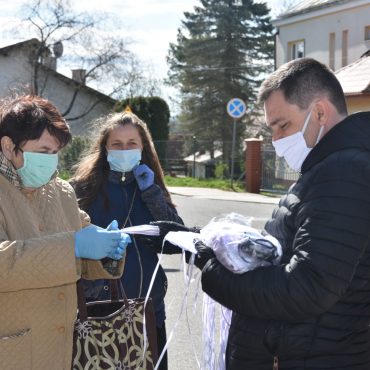 Wysoki mężczyzna przekazuje dwóch kobietom maseczki darmowe