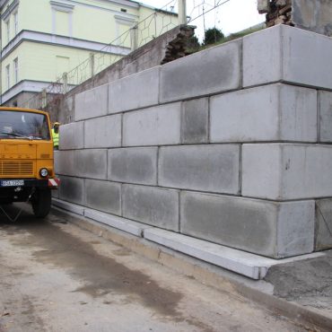 Pracownicy budują mur na drodze głównej.