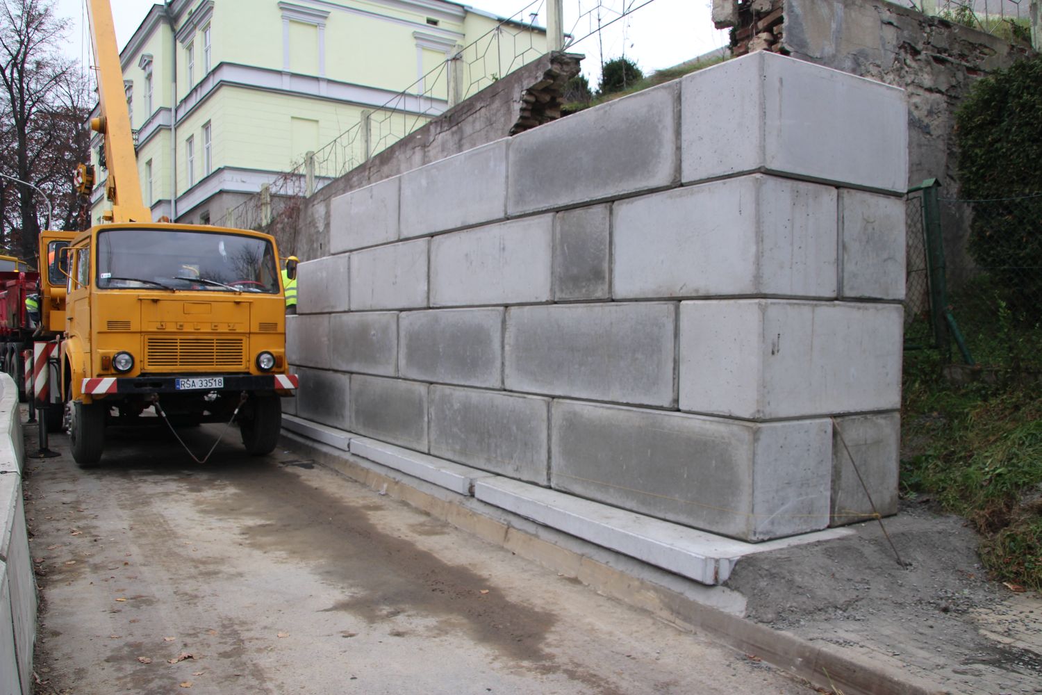 Pracownicy budują mur na drodze głównej.