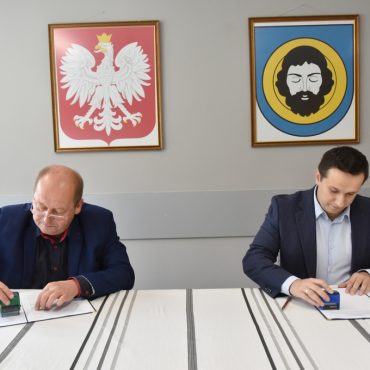 Młody mężczyzna i mężczyzna w średnim wieku mężczyzna siedzą przy stole i przykładają pieczątki na dokumenty. pisane wzajemnie umowy.