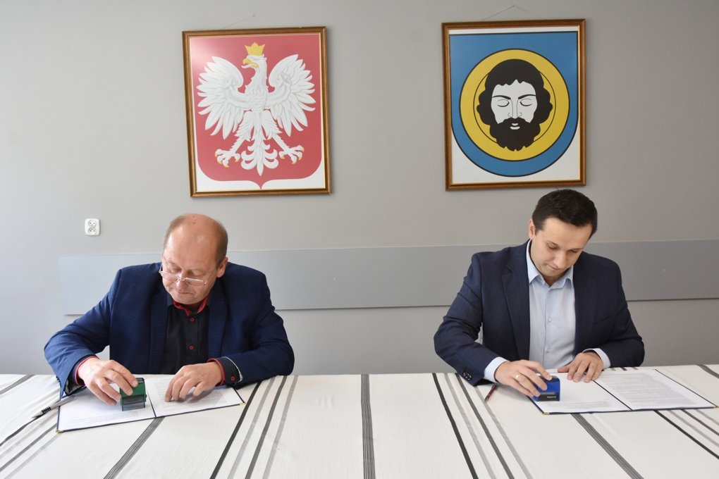 Młody mężczyzna i mężczyzna w średnim wieku mężczyzna siedzą przy stole i przykładają pieczątki na dokumenty. pisane wzajemnie umowy.