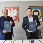 Młody mężczyzna i w średnim wieku mężczyzna trzymają podpisane wzajemnie umowy.