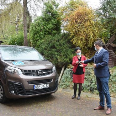 Młody mężczyna przekazuje kluczki kobiecie do nowego samochodu.