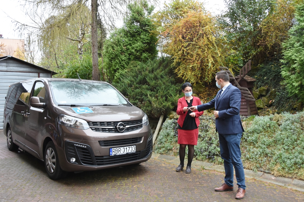 Młody mężczyna przekazuje kluczki kobiecie do nowego samochodu.
