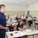 Młody mężczyzna trzyma mikrofon starszej kobiecie, która odpowiada na pytania.