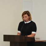 Młoda pani w czarnej sukience przemawia na mównicy.