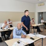 Młody mężczyzna trzyma mikrofon mężczyźnie w średnim wieku, który zadaje pytanie.