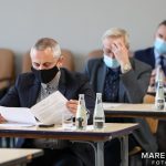 Grupa trzech mężczyzn w garniturach przegląda dokumenty. Każdy z nich znajduje się przy własnym stoliku.