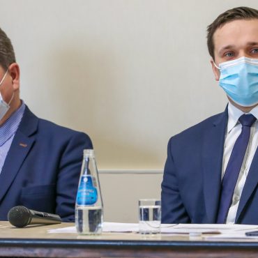 Dwóch mężczyzn w garniturach siedzi przy stoliku.