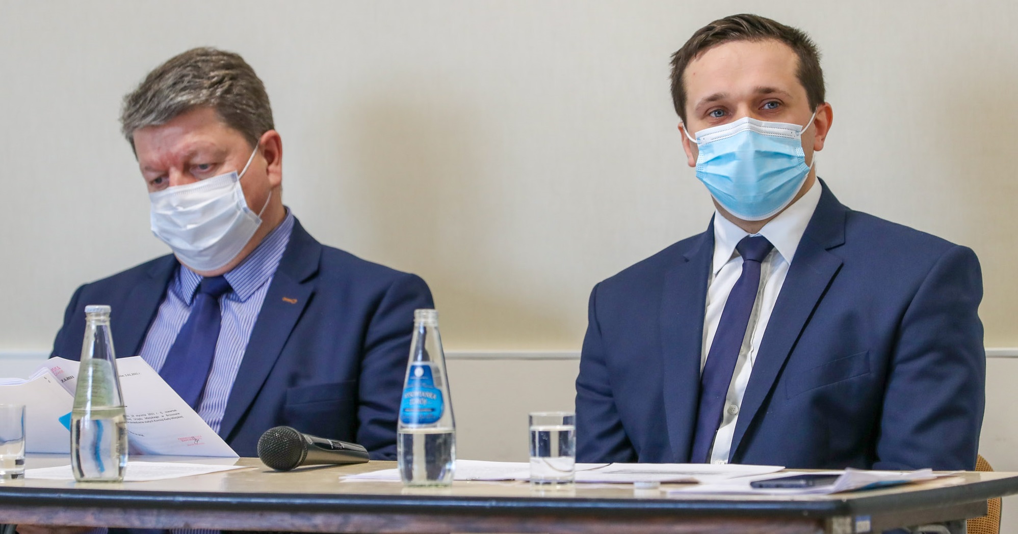 Dwóch mężczyzn w garniturach siedzi przy stoliku.