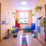 Pomieszczenie do zabaw w szkole, we wnątrz basen z kulkami, zabawki, mata do chodzenia.