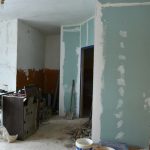 Obdarte mieszkanie. Z boku stoją postawione ścianki działowe, podłoga bez paneli.