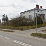 Budynek z jasną elewacją stoi, przy skrzyżowaniu dwóch ulic.