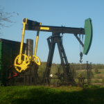 Urządzenie pompowe stoi na terenie zielonym. Obok budynek koloru zielonego.