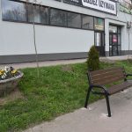 Drewniana ławka ustanwiona na płytkach w centrum miasta.