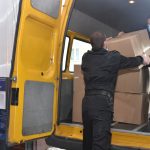 Dwóch mężczyzn pakuje pudełka do samochodu strażackiego.