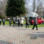 Dwóch młodych mężczyzn w stroju strażaka rozdają maseczki mieszkańcom.