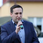 Młody mężczyzna przemawia do mikrofonu.