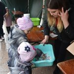 Dwie małe dziewczynki wybierają z miętowej miski tatuaże.