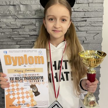 Dziewczynka o jasnych włosach trzyma w rękach puchar i dyplom.