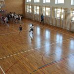 Dzieci w strojach sportowych biegają na sali gimnastycznej.