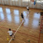 Dzieci w strojach sportowych biegają na sali gimnastycznej.