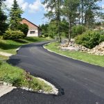 Nowa droga wyłożona asfaltem. Droga biegnie między zielonymi krajobrazami.