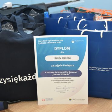 Nagrody leżą w reklamówkach na stole, obok piłki, a także dyplom.