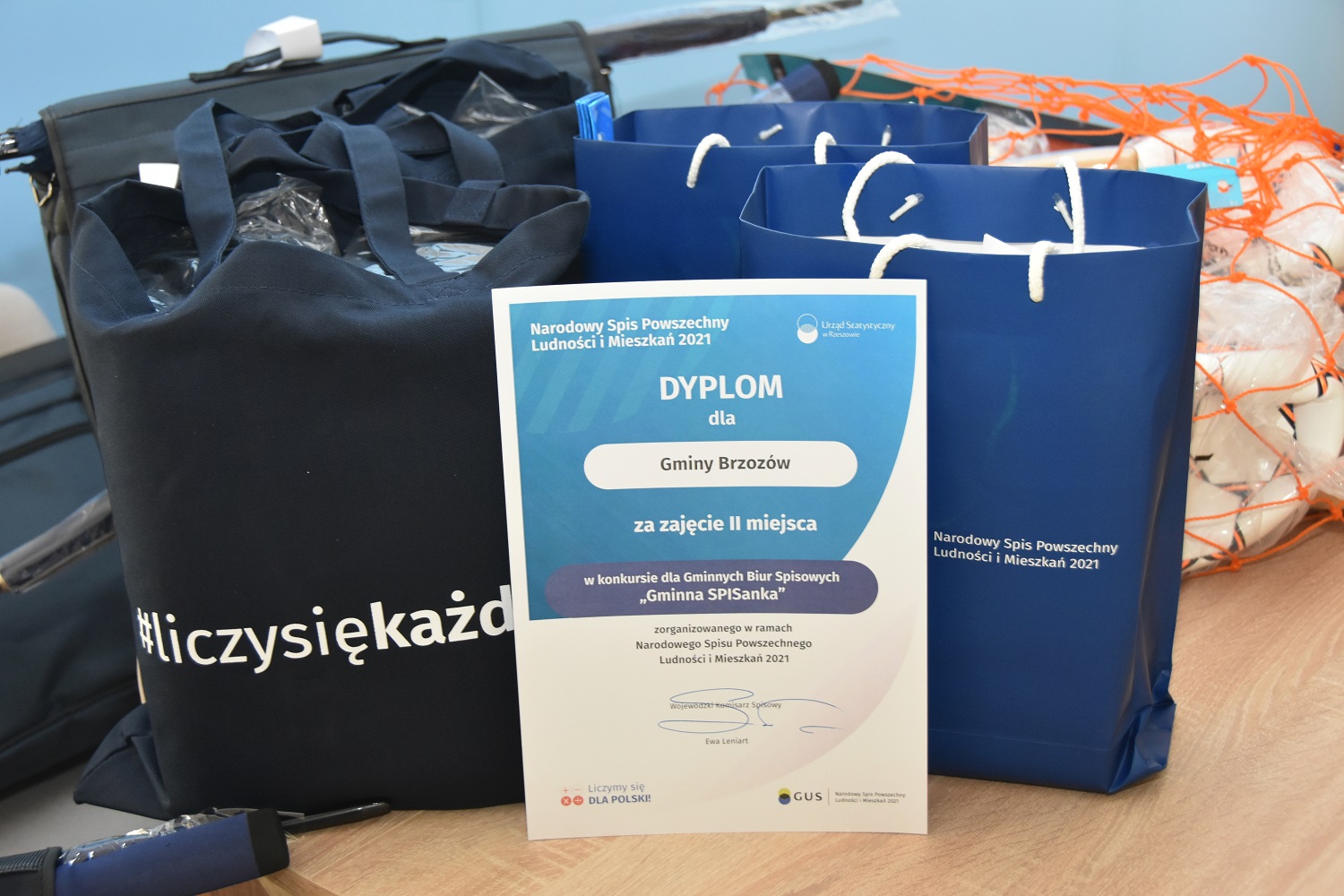 Nagrody leżą w reklamówkach na stole, obok piłki, a także dyplom.