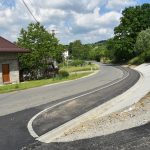 Nowy chodnik po prawej stronie drogi powiatowej. Po lewej stronie tereny zielone zabudowane przez domy jednorodzinne.