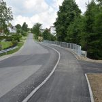 Nowy chodnik wzdłuż drogi powiatowej, w da;szej części po prawej stronie barierki.