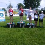 Grupa dzieci ubrana na sportowo stoi na podium z dyplomami.